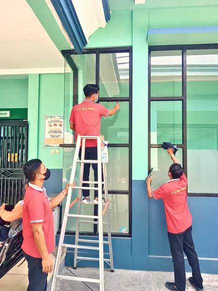 Petugas membersihkan kaca jendela gedung